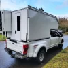 White lightweight overland F350 slide-in on neighborhood street