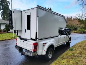 White lightweight overland F350 slide-in on neighborhood street